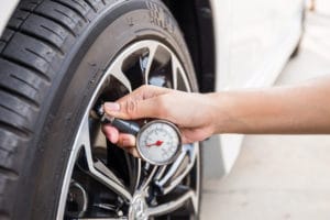 checking tire pressure with air gauge