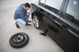 man changing flat tire with spare tire