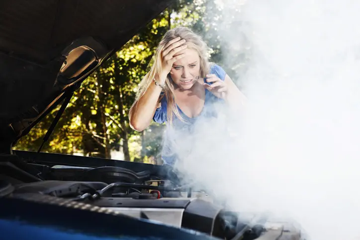 Stressed woman looking at her smoking engine.