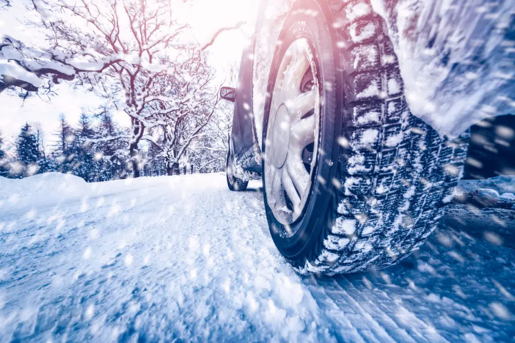 Car tires on winter road covered with snow. Vehicle on snowy roadway.