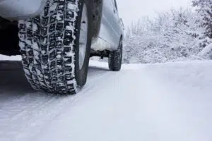 Close up of car tire on wintry road covered with snow