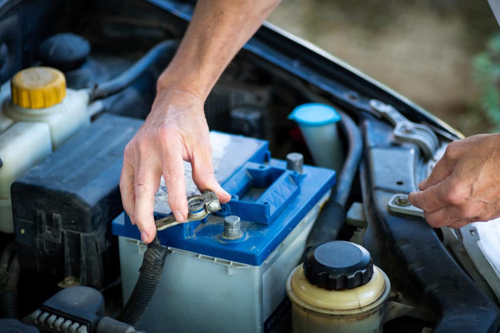 Man connecting the car battery to the vehicle with a wrench closeup