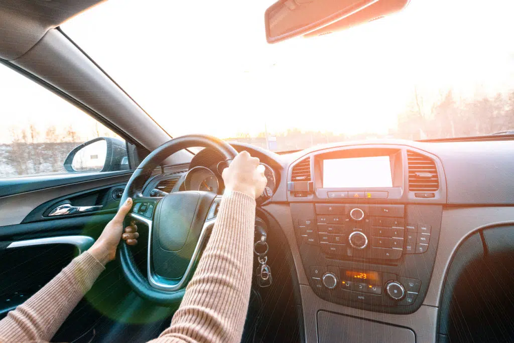 interior vehicle view of a woman driving a car on a sunny clear day