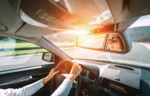 smiling woman wearing sunglasses driving car safely on open sunny highway