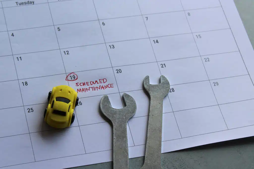 Car scheduled maintenance concept. Toy car, tools and calendar with text SCHEDULED MAINTENANCE written in and date circled