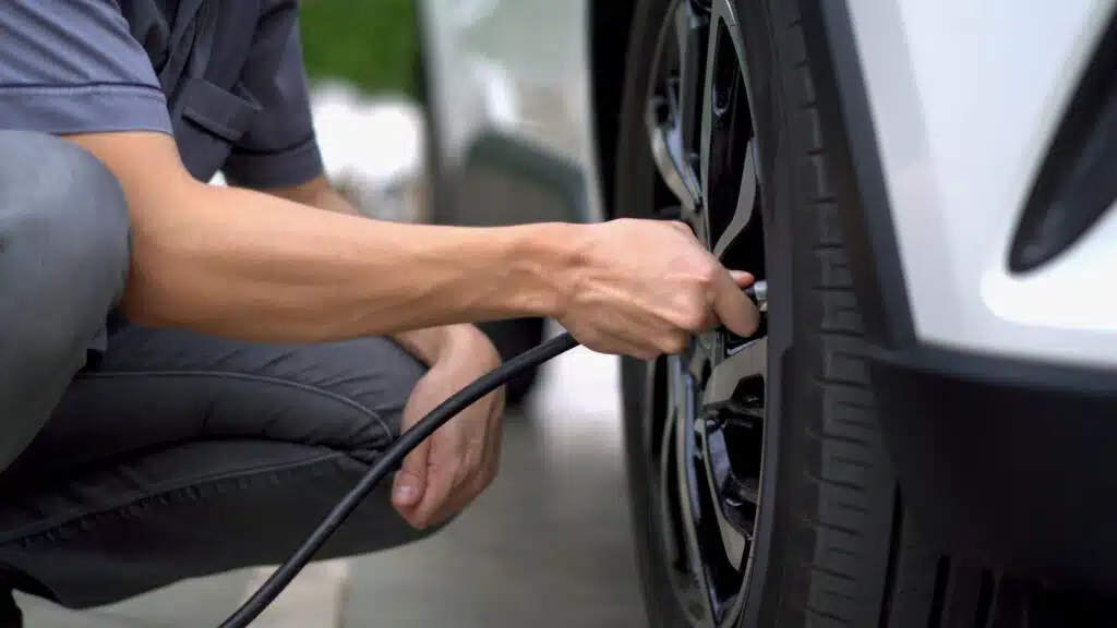man filling air in the tires of his car (inflating tire)