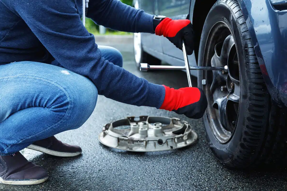 car owner changing flat tire on vehicle